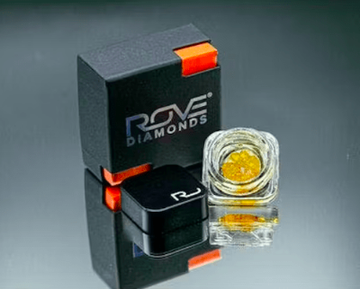 Black Rove Diamonds box with mint corner accents beside a clear glass jar of amber crystalline concentrate, the packaging used for Durban Poison