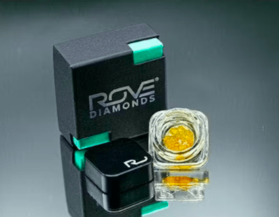 Black Rove Diamonds box with mint corner accents beside a clear glass jar of amber crystalline concentrate, the packaging used for Wedding Cake